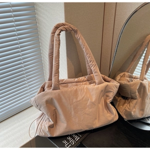 Close-up of quilted nylon tote bag with wide straps and drawstring details in soft apricot