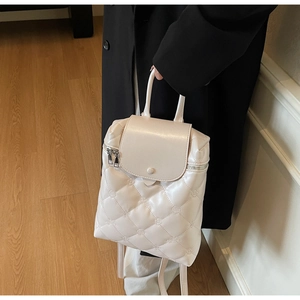 Detail of white quilted backpack featuring floral embroidery and glossy faux leather finish