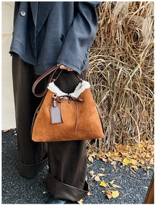 Detailed shot of brown suede shoulder bag with plush lamb wool trim and leather bow tie