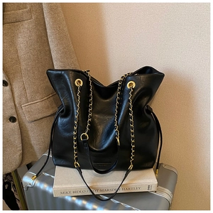 Close-up of black PU leather bucket bag featuring gold eyelets and woven chain strap