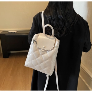 Detailed view of quilted beige mini backpack with floral stitching and silver zippers