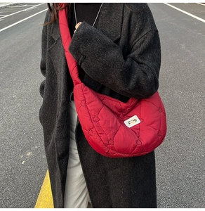 Detail shot of a red quilted crossbody bag with heart patterns and a sunny patch