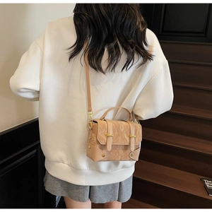 Détail du petit sac carré plissé marron clair porté en bandoulière sur modèle