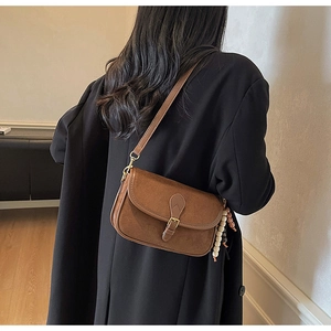 Close-up of retro brown frosted shoulder bag with white bead tassel on black coat