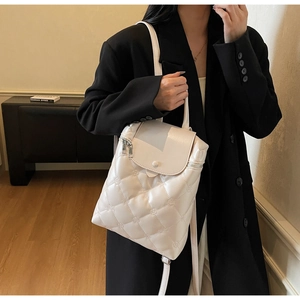 Detail of white quilted backpack with floral embroidery and elegant flap design