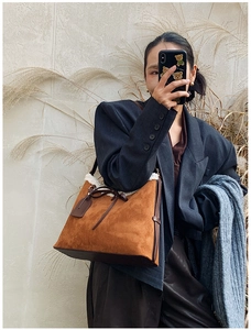 Detail of caramel suede shoulder bag with white faux shearling trim and leather straps