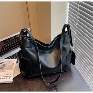 Close-up of black matte PU leather shoulder bag with adjustable strap and side pockets