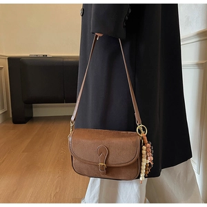 Detail of vintage brown suede crossbody bag featuring ethnic wood bead charm accessory