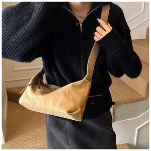 Détail d'un sac bandoulière en daim kaki avec bandoulière large et fermeture éclair