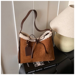 Detailed view of brown suede tote bag with white faux shearling trim and bow detail