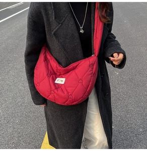 Detail of red heart-quilted crossbody crescent bag with stylish brand label detail