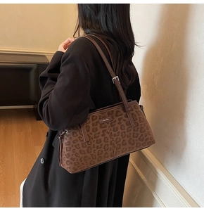Detail of leopard print underarm bag with metal plaque and side drawstring on model