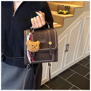 Detail of vintage brown leather handbag with contrast stitching and teddy bear charm