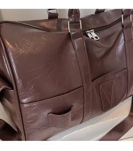 Détail du sac de voyage en cuir marron foncé avec texture souple et fermetures