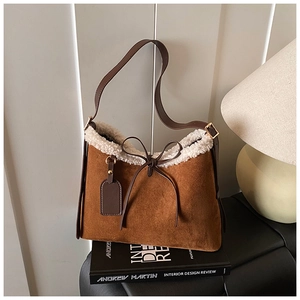 Detailed close-up of brown suede shoulder bag with white faux shearling trim and bow detail