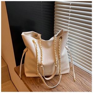 Detailed view of white faux leather bucket bag with gold chain and lychee texture