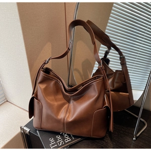 Detail of brown matte leather hobo bag with side flap pockets and vertical stitching