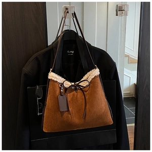 Detail of brown suede tote bag featuring white faux fur trim and leather bow decoration