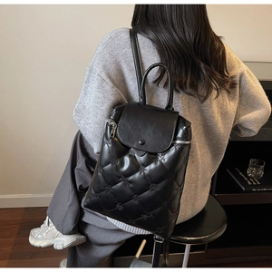 Detail of black quilted backpack with floral embossing and elegant flap closure