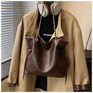 Detailed close-up of dark brown leather bucket bag with chain strap and drawstring detail