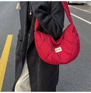 Detail of red quilted heart-pattern shoulder bag with fluffy down texture and planet charm