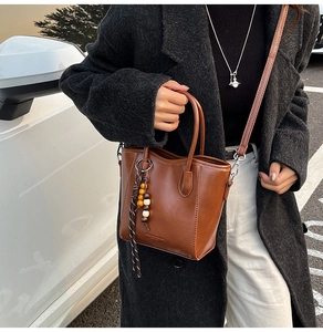 Détail du sac seau marron avec gland perlé et logo FASHION & BAGS embossé
