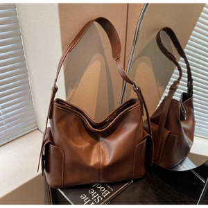 Detail of dark brown leather shoulder bag with side flap pockets and premium stitching