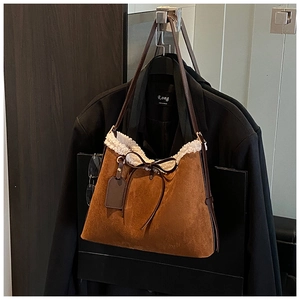 Detail of suede bucket bag with shearling trim and leather bow on a blazer