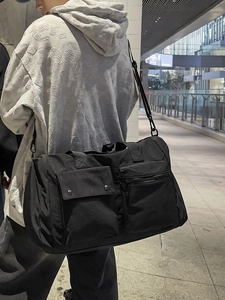 Large black fitness travel bag with adjustable strap worn by a model in urban setting