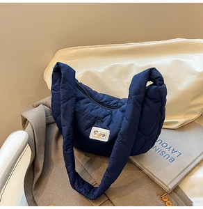 Detail of navy blue heart-quilted cloud bag with a decorative pearl S patch on fabric