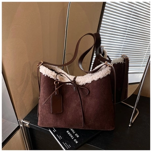 Detail view of brown suede bucket bag featuring white faux fur trim and bow detail