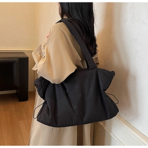 Detail of black quilted puffer shoulder bag with side drawstring showing texture and large capacity