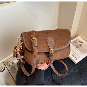 Detailed view of a brown matte leather crossbody bag featuring vintage gold buckle and beads