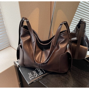 Macro view of dark brown tote bag showing side pockets and soft leather texture