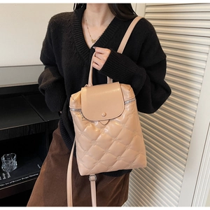 Detail of beige quilted backpack showing PU leather texture and brand embossed patterns