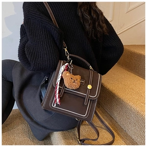 Detail of vintage brown leather backpack with bear charm and scarf on stairs