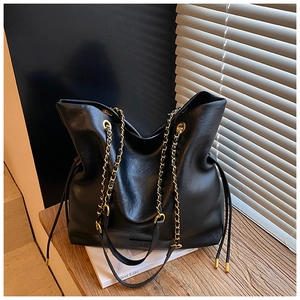Detail of black pebbled leather bucket bag with chain strap on a wooden bench