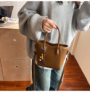 Sac seau en cuir marron avec poignées et un charmant pompon en perles colorées