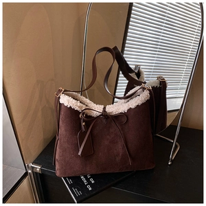 Detail view of suede underarm bag with white faux fur trim and bow tie accessory