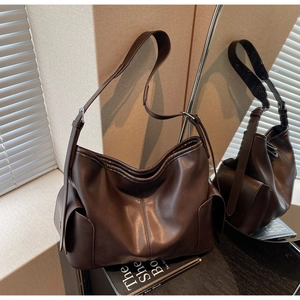 Macro detail of soft coffee brown leather texture and slouchy design on a large hobo bag