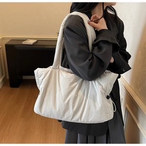 Detail view of large quilted puffer tote bag in off-white nylon with adjustable drawstrings