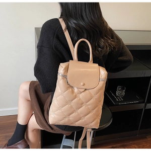 Detail of beige quilted backpack with diamond stitching and small floral embroidery