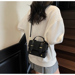 Detail of black faux fur shoulder bag with gold metal buckle and leather handle texture