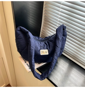 Detail of navy blue quilted shoulder bag featuring heart pattern stitching and logo plaque