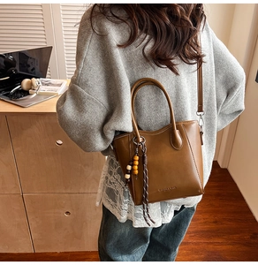Détail d'un sac seau marron avec charme en perles de bois et texture cuir élégante
