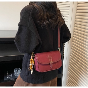 Detail of burgundy vintage crossbody bag with matte finish and wooden bead charm