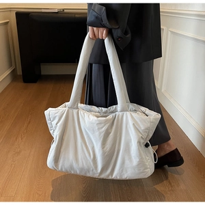 Detailed close-up of quilted nylon tote bag texture and adjustable side drawstring