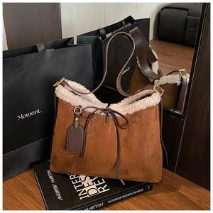 Detail of dark brown suede shoulder bag with plush faux fur trim and bow decoration