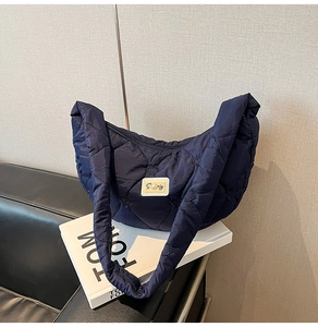 Close-up of heart-shaped quilted texture on a blue puffer bag with a pearl tag detail