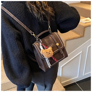 Detail of dark brown leather mini bag with contrast stitching and teddy bear charm